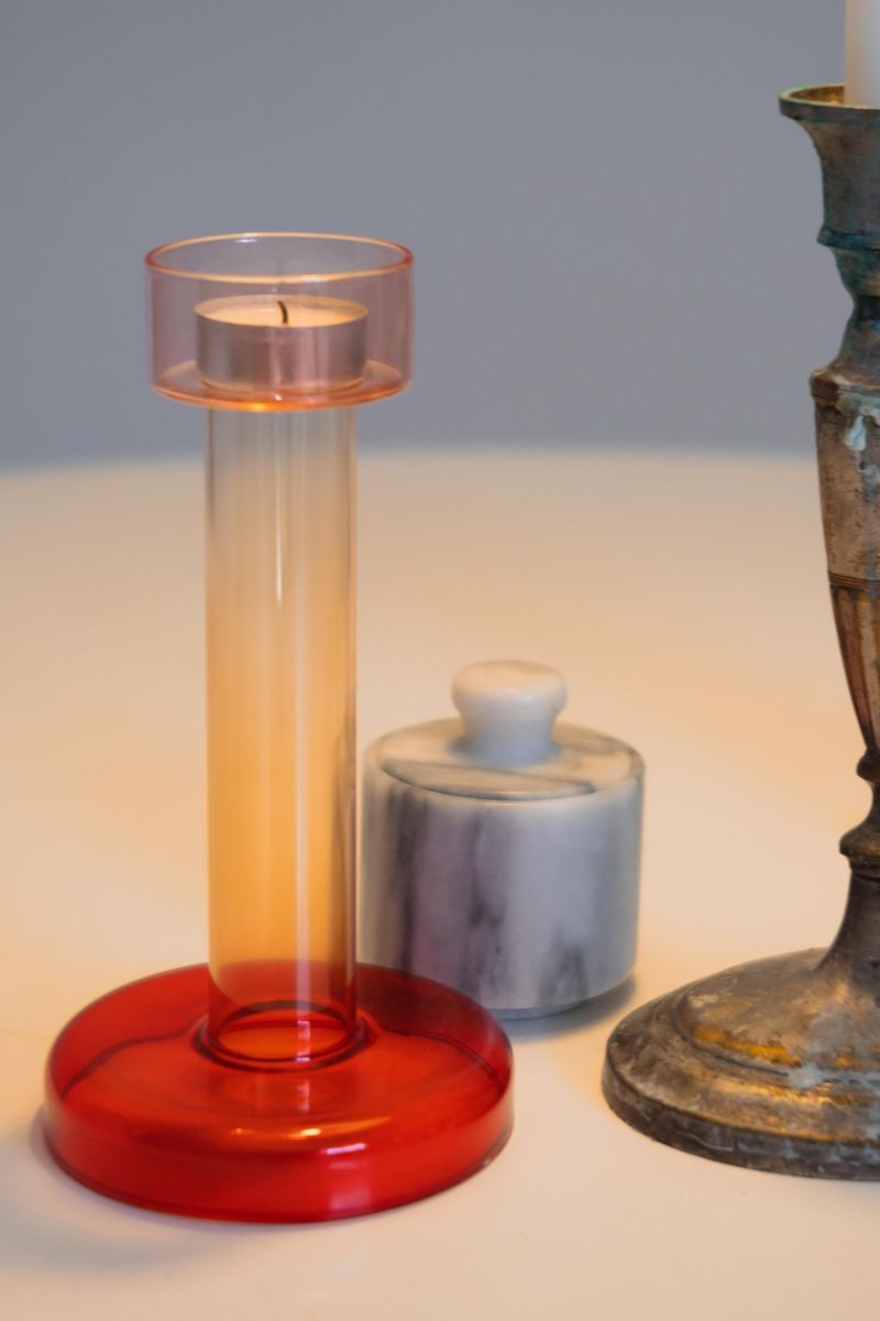 Kerzenständer aus rotem Glas neben einem alten Messingleuchter