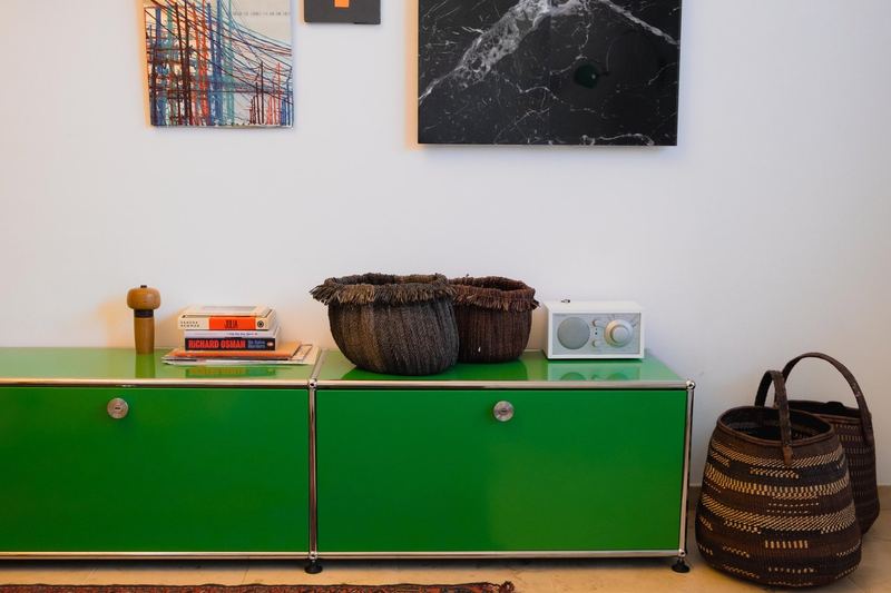 Grünes Sideboard mit Korb und Kunst an der Wand