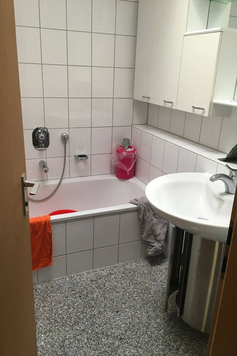 Altes Badezimmer mit eingebauter Wanne, Waschbecken und gefliesten Wänden